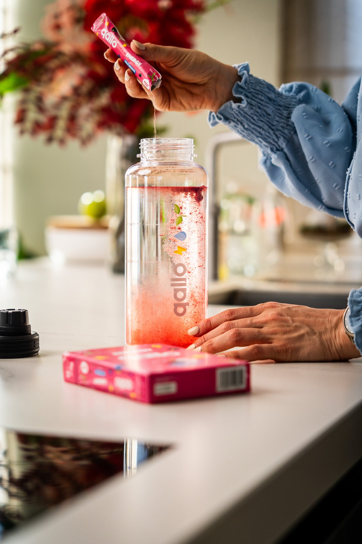 Een zakje Qallo Energy Wild Berries wordt in een drinkfles gegoten
