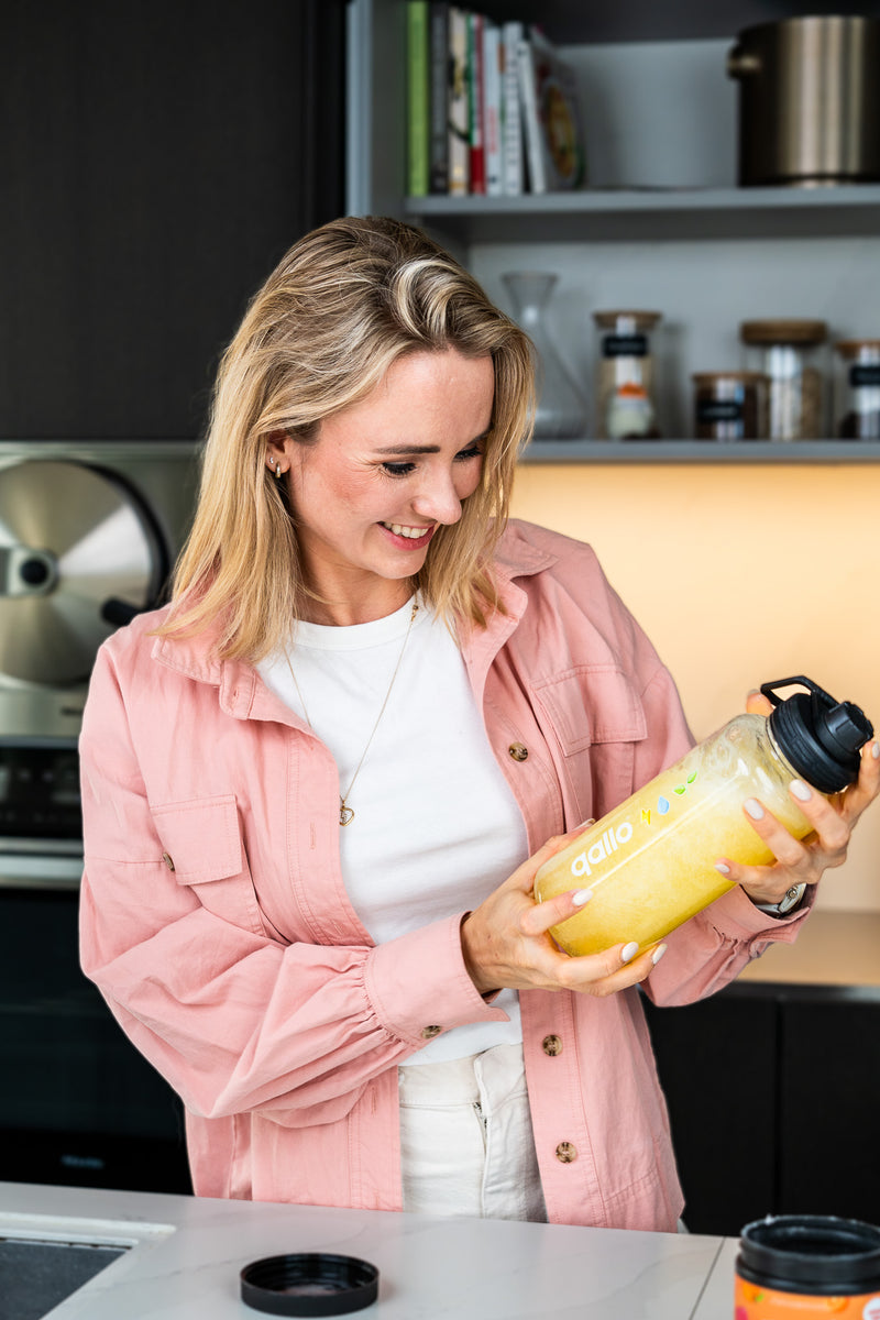Vrouw schudt een Qallo drinkfles in de keuken